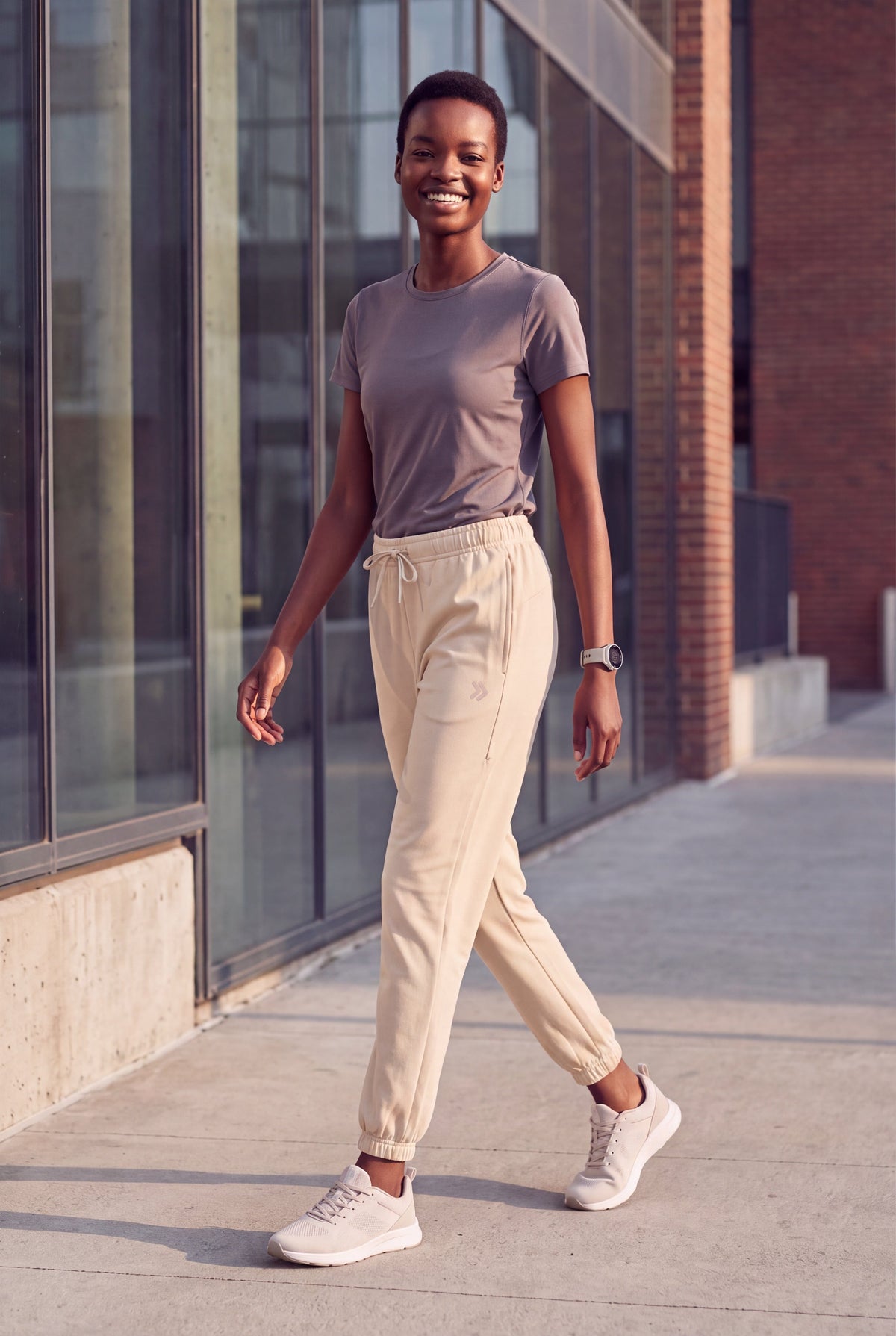 A woman wearing MOVE sport apparel beige French terry joggers with a drawstring waist and ribbed cuffs outdoors.