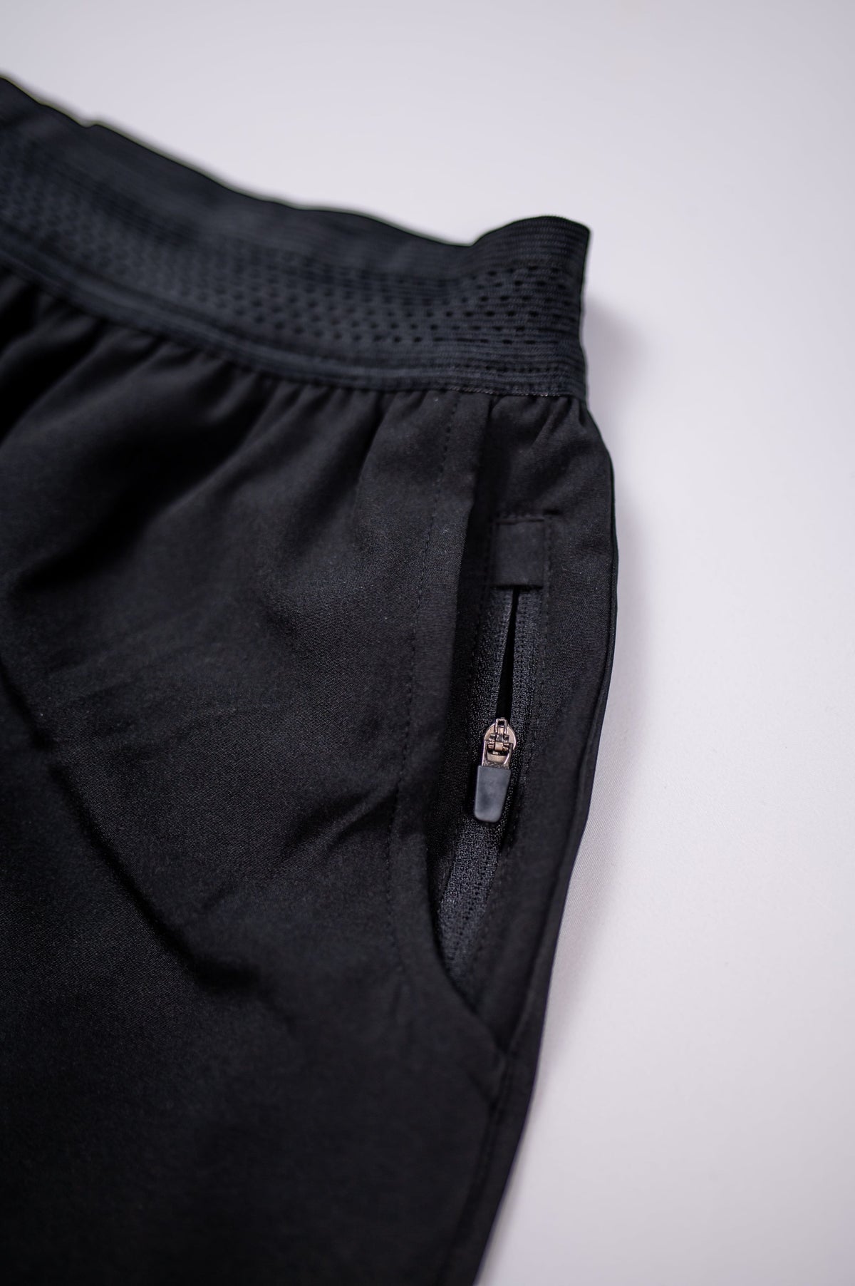 MOVE sport apparel men's black running shorts featuring a breathable waistband and a secure zippered side pocket.