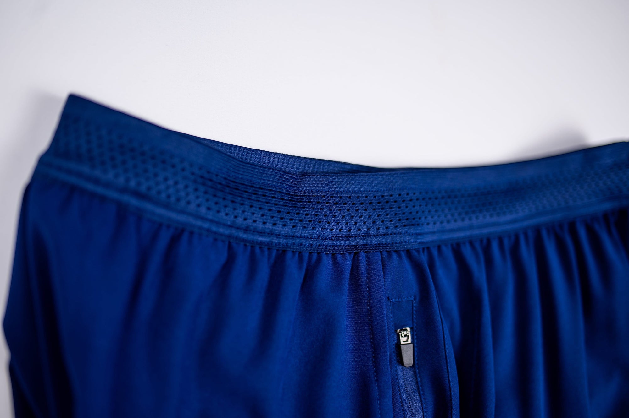 MOVE sport apparel men's blue running shorts featuring a breathable mesh waistband and a secure zippered pocket.