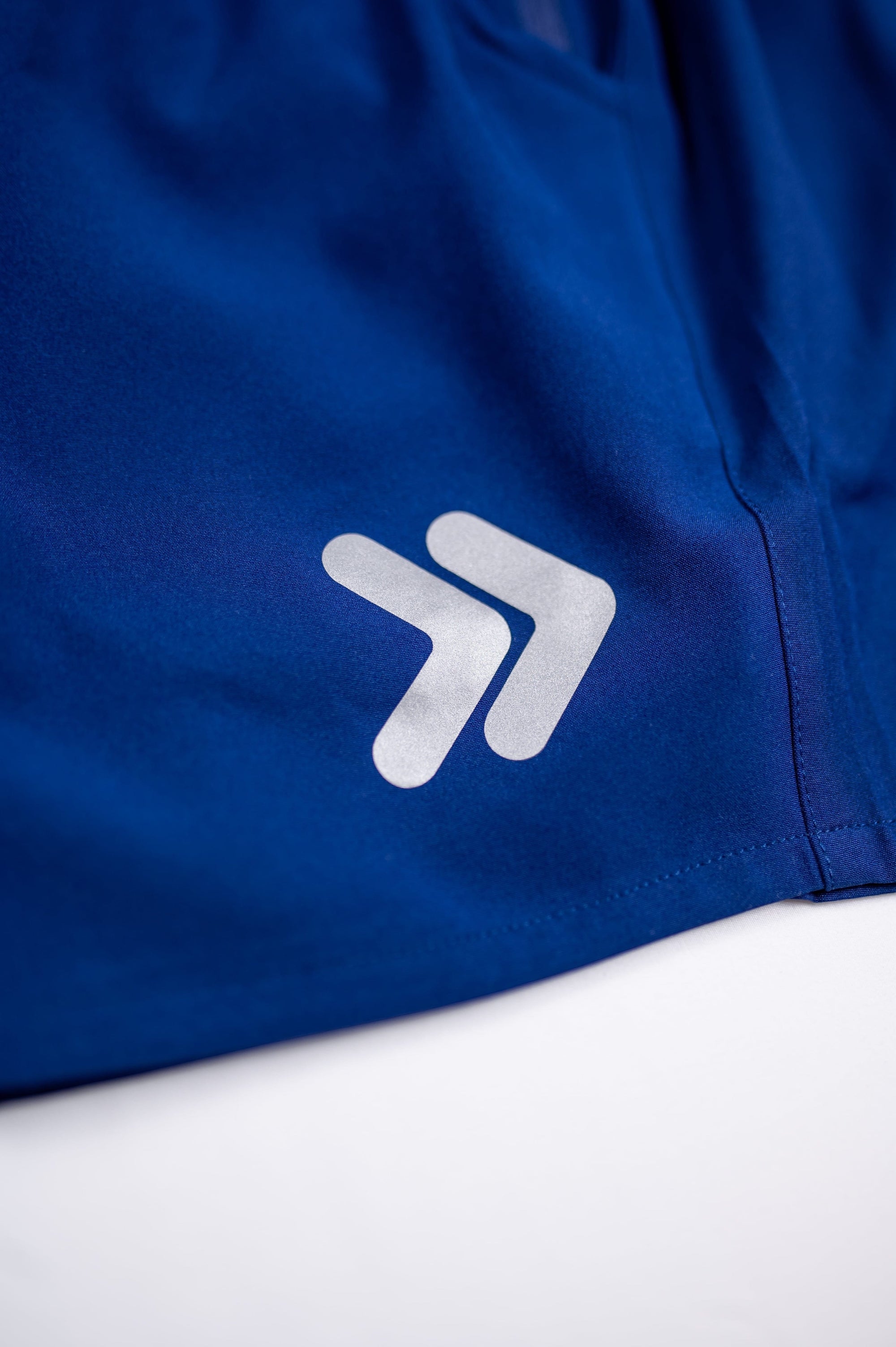 MOVE sport apparel men's royal blue running shorts featuring a reflective logo detail on the fabric.