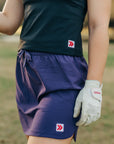 MOVE sport apparel black cropped tank top paired with a purple athletic skort and a white golf glove