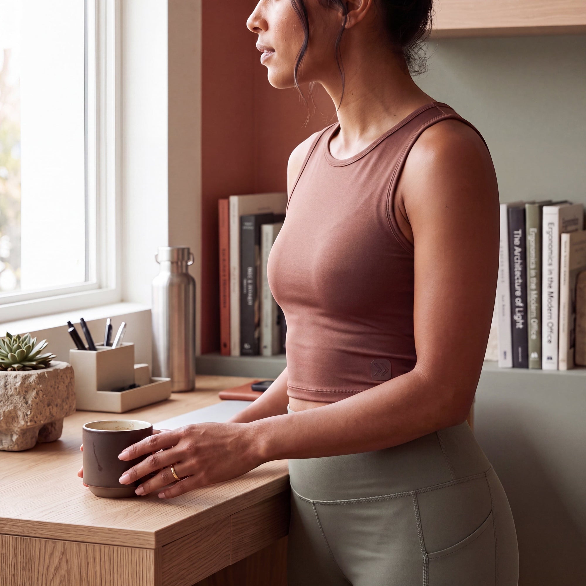 MOVE sport apparel women's mauve cropped tank top in stretchy fabric, worn by a woman standing at a desk.
