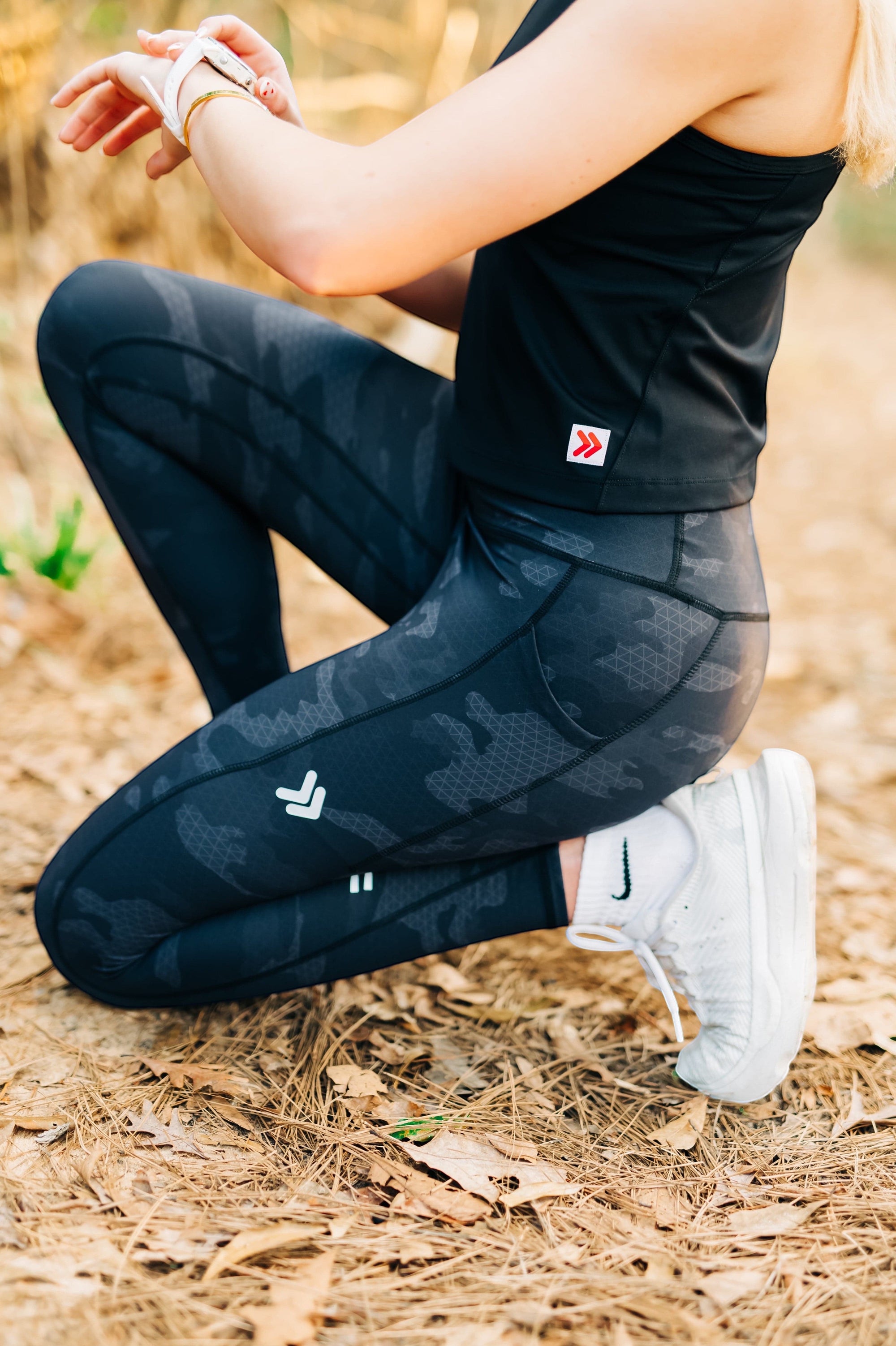 MOVE sport apparel women's black cropped tank top paired with dark grey camouflage leggings during an outdoor workout