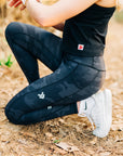 MOVE sport apparel women's black cropped tank top paired with dark grey camouflage leggings during an outdoor workout