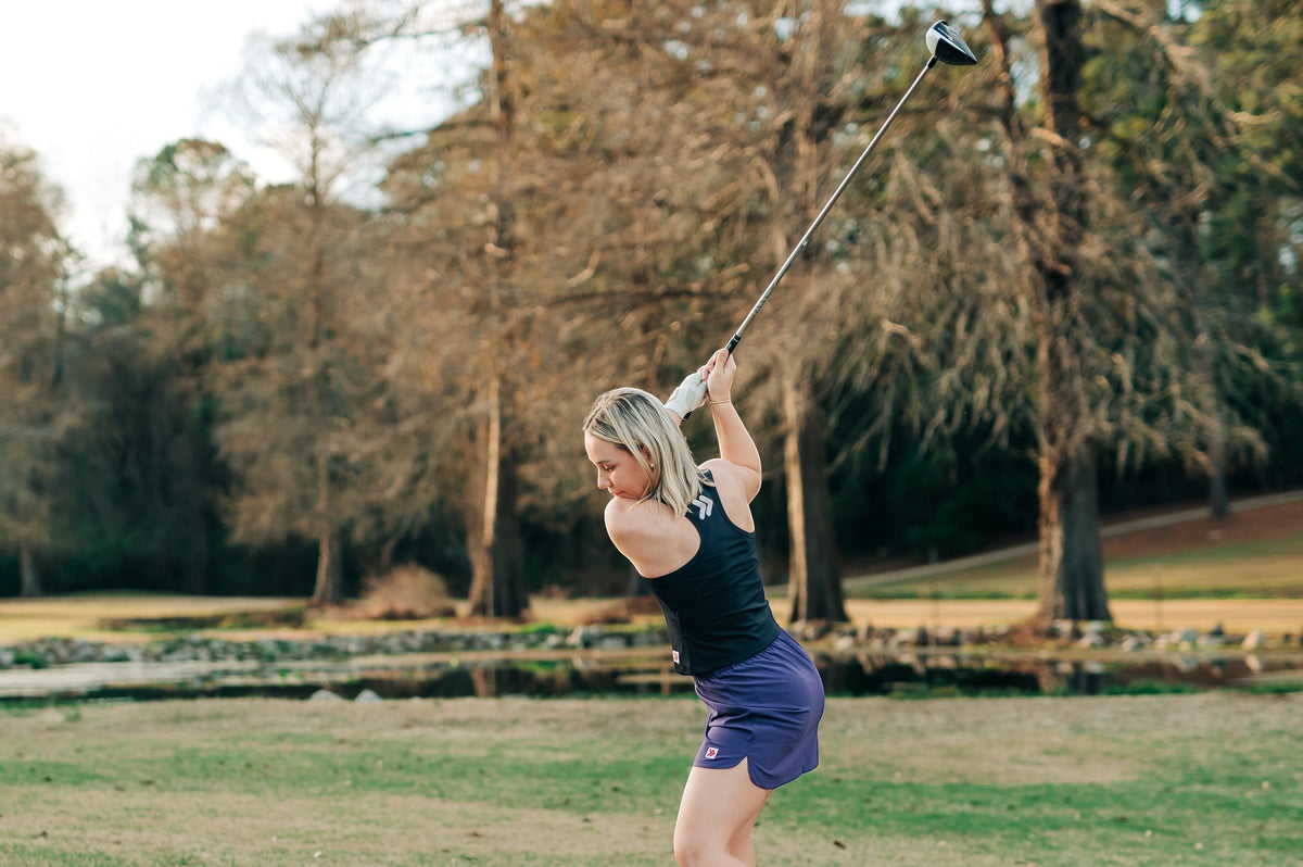 MOVE sport apparel black cropped tank top worn by a woman swinging a golf club on a course