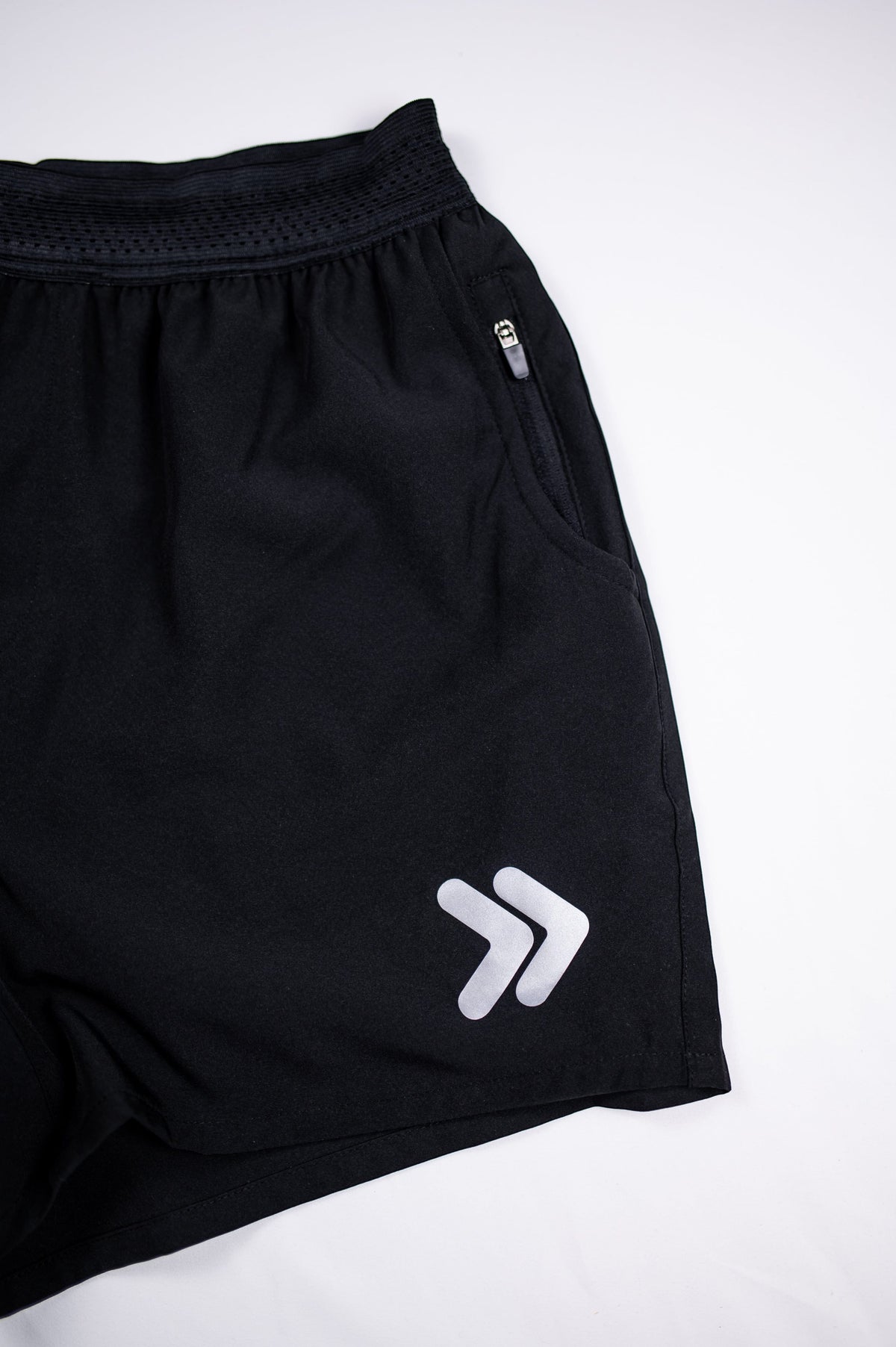 MOVE Sport Apparel men’s Performance 5 Inch Running Shorts: Black shorts detail showing the white double-chevron embellishment.