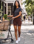 MOVE sport apparel high-rise brown athletic shorts with side pockets worn by a woman walking with a grocery cart.