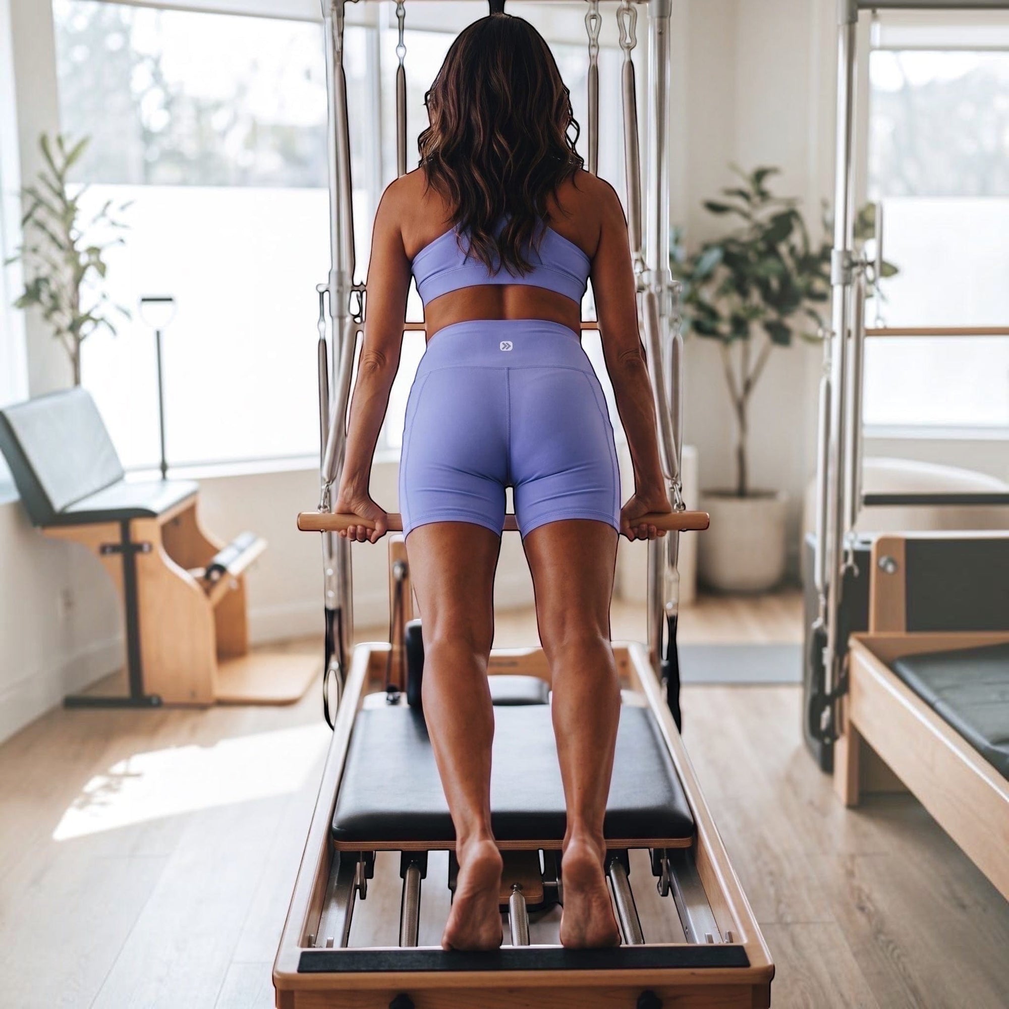 MOVE sport apparel lavender high-rise athletic shorts on a woman using a pilates reformer machine in a studio