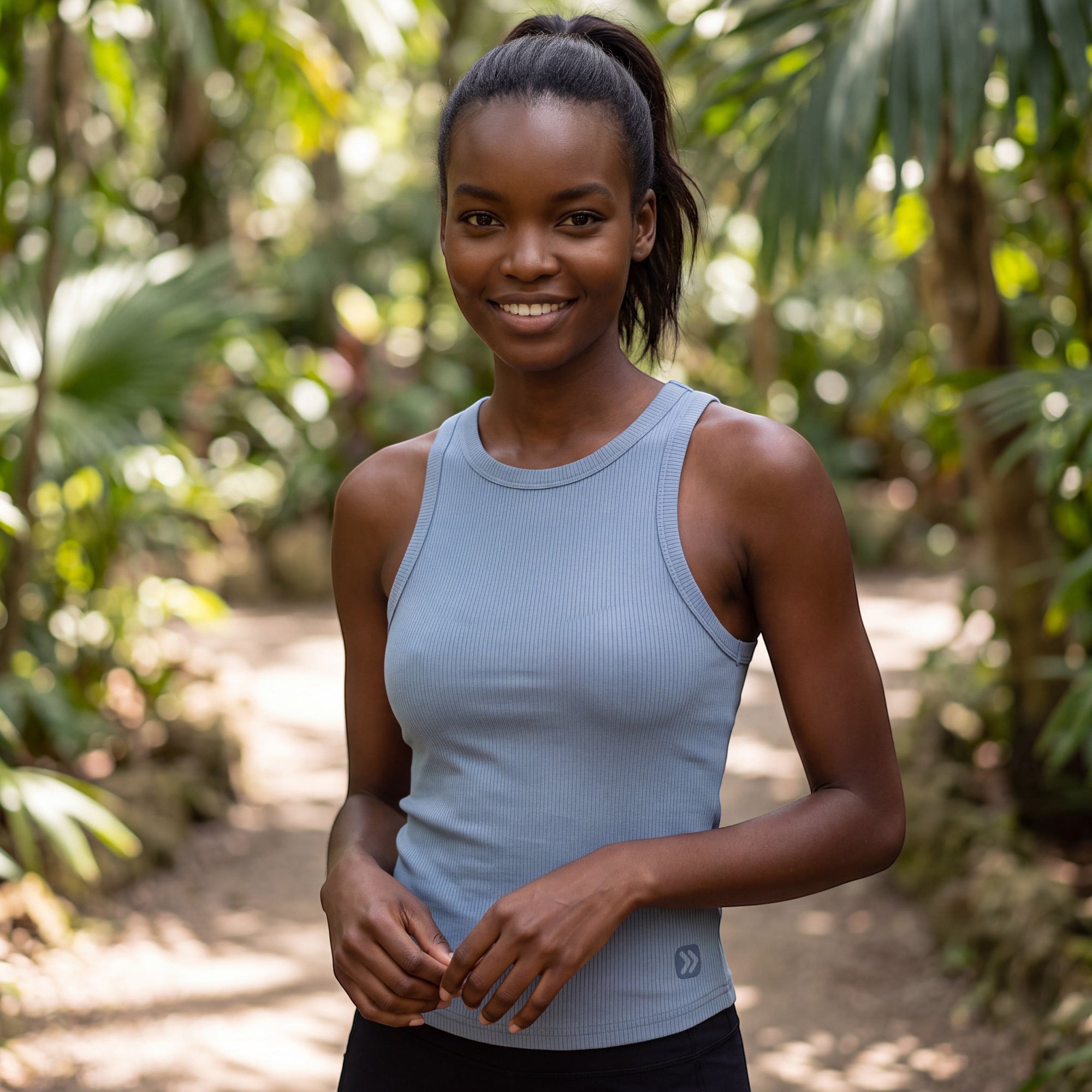 MOVE sport apparel bamboo crop tank in light blue, worn by a woman in a lush tropical garden setting.