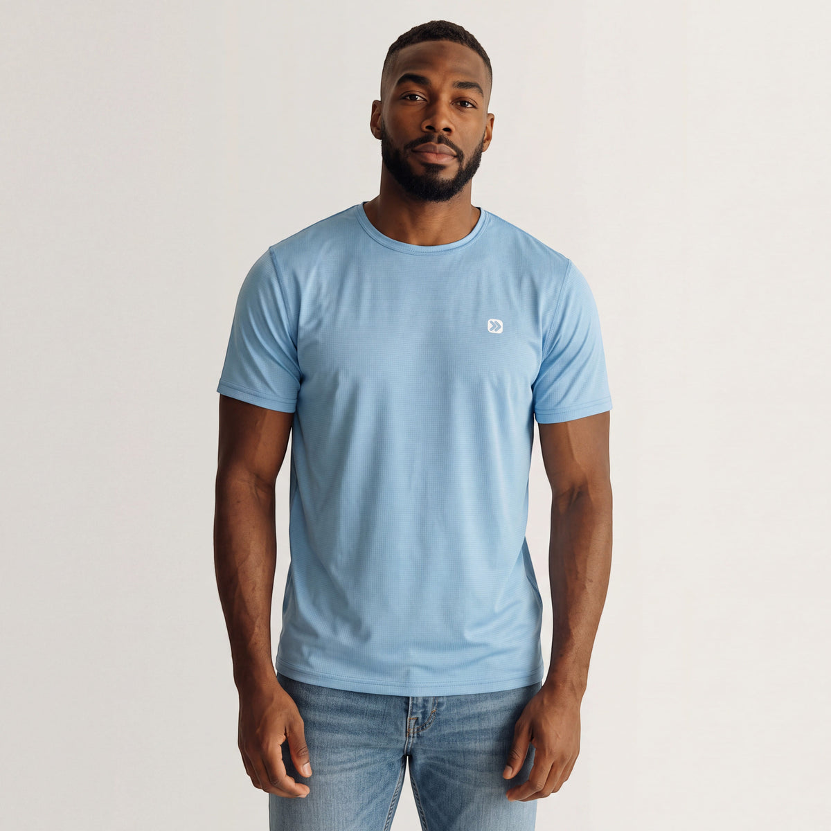 MOVE Sport Apparel Blaze Training T-Shirt in Forget-Me-Not blue, front studio view on an adult man with the original small white chest embellishment.