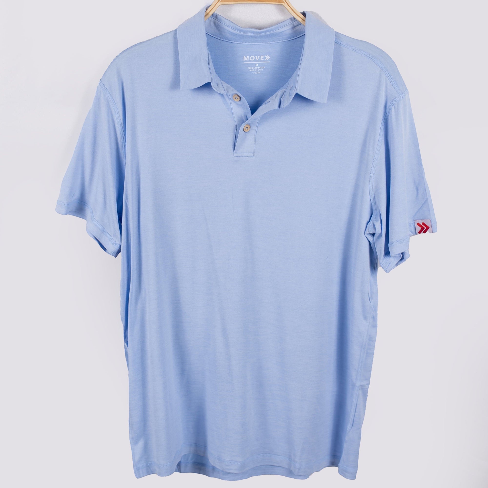 MOVE sport apparel light blue moisture-wicking polo shirt with a classic collar and button placket on a hanger