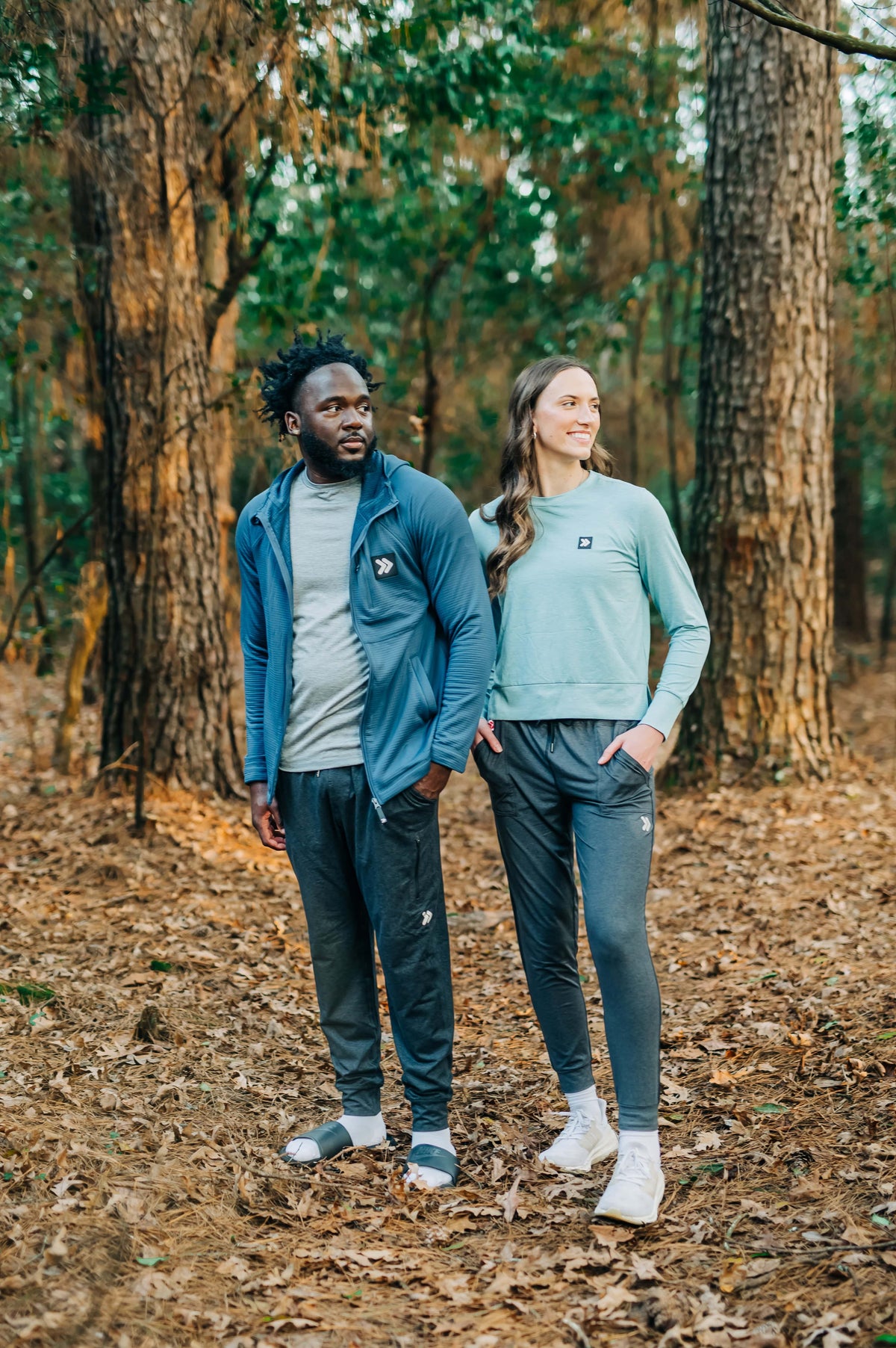 MOVE sport apparel woman wearing a light blue long sleeve crewneck sweatshirt with ribbed cuffs in a forest setting