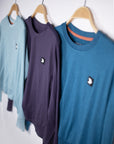 MOVE sport apparel crewneck sweatshirts in light blue, dark purple, and teal hanging on wooden hangers