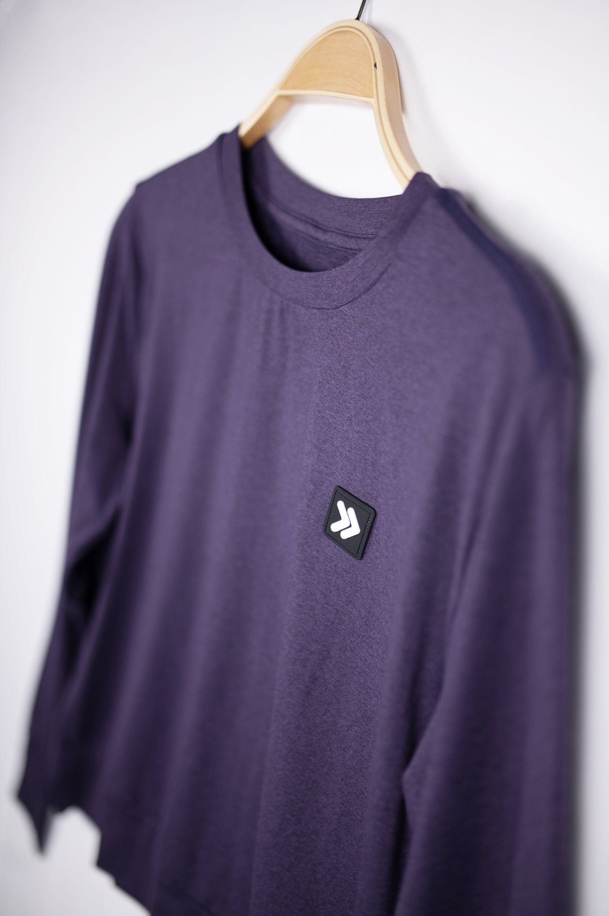 MOVE sport apparel purple long sleeve crewneck sweatshirt with signature Black Label patch on a wooden hanger