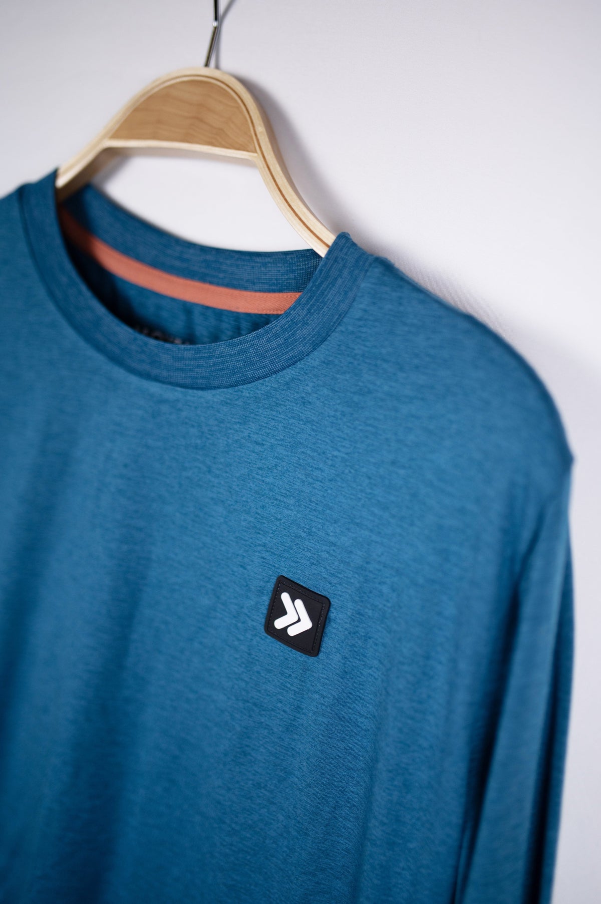MOVE sport apparel blue heathered long sleeve crewneck sweatshirt with a signature Black Label patch on a hanger