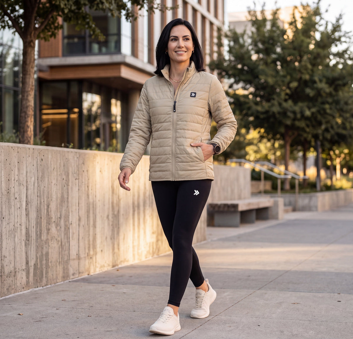 Woman wearing the MOVE Sport Apparel women’s Silver Birch Lightweight Down Jacket with black leggings on an urban walk.