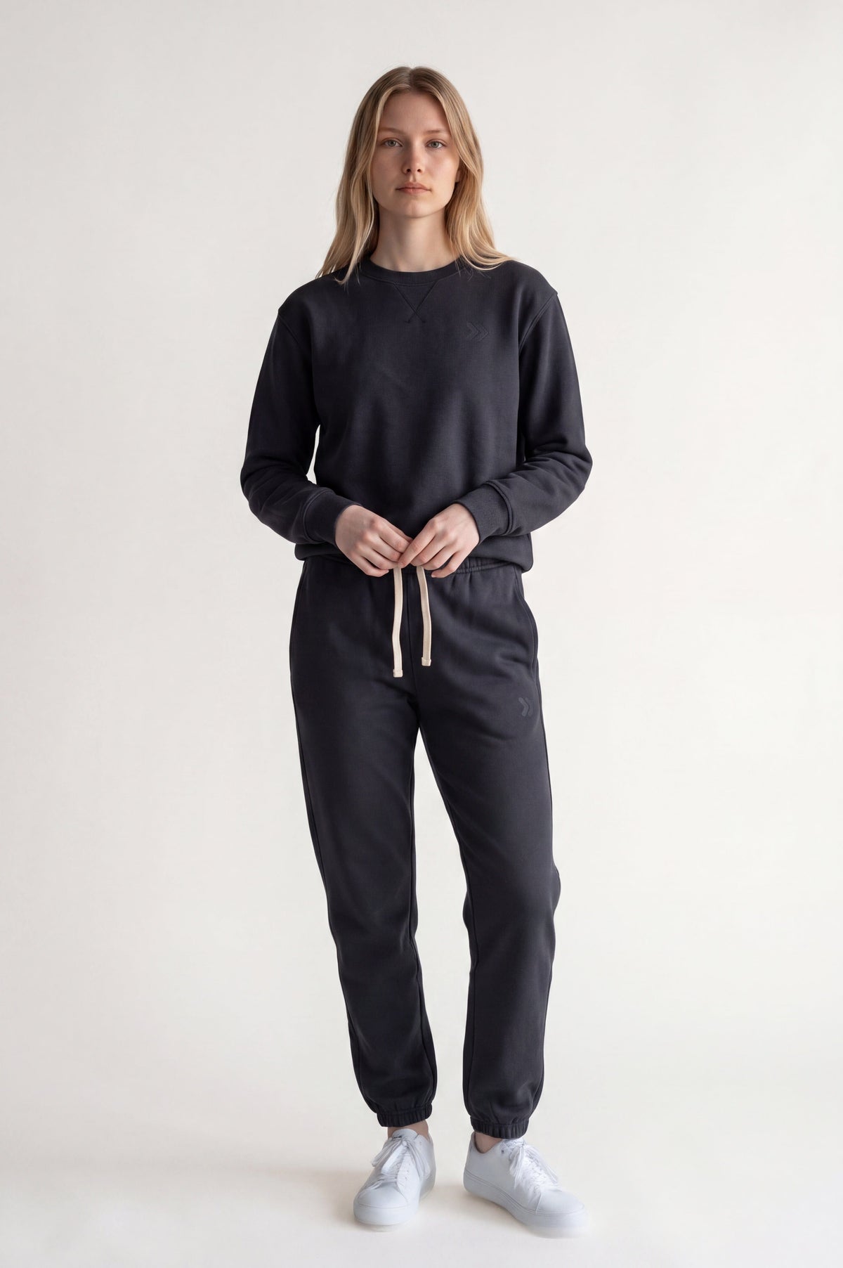 Full body studio view of a woman wearing MOVE Sport Apparel French Terry Joggers in Volcanic Ash with a dark sweatshirt.