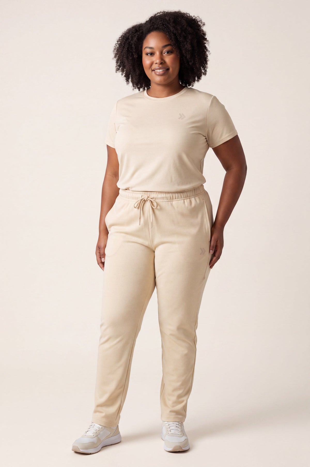 Woman wearing MOVE Sport Apparel French Terry Joggers in Natural with a light T-shirt in a neutral studio.