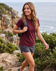 MOVE Sport Apparel women’s Merino Short Sleeve T-Shirt: Woman wearing Oxblood Red Merino Short Sleeve T-Shirt with grey shorts on a coastal trail.
