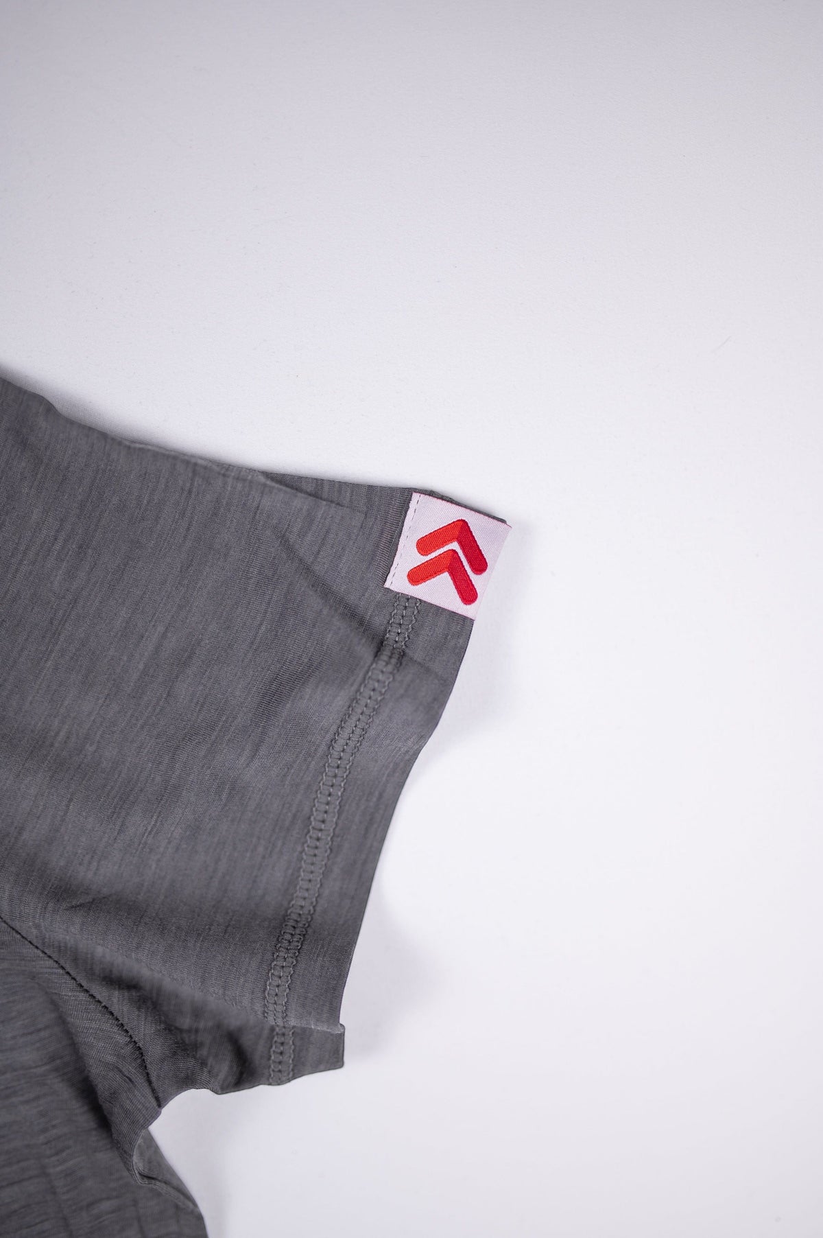 MOVE Sport Apparel women’s Merino Short Sleeve T-Shirt: Close view of the original red-and-white sleeve tab on the Granite Gray Merino shirt.