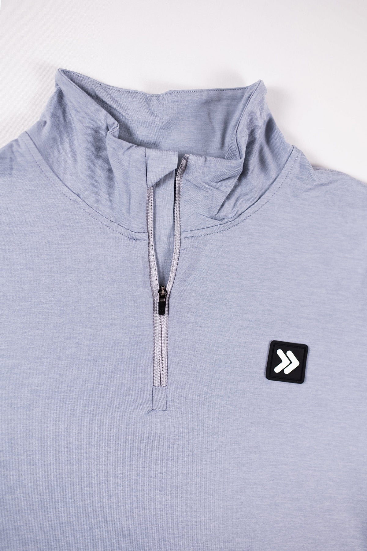 Close view of the collar, quarter zipper and original chest patch on the MOVE Sport Apparel Women’s Essential Quarter Zip in Silver Cloud.