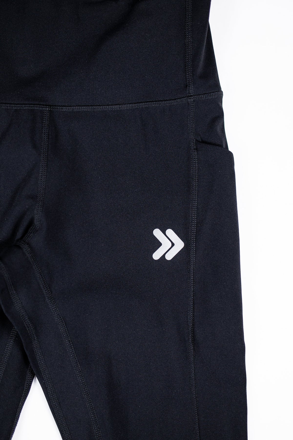 Close-up of the original white double-chevron thigh embellishment and side pocket on black MOVE Sport Apparel women’s Brushed Running Leggings.