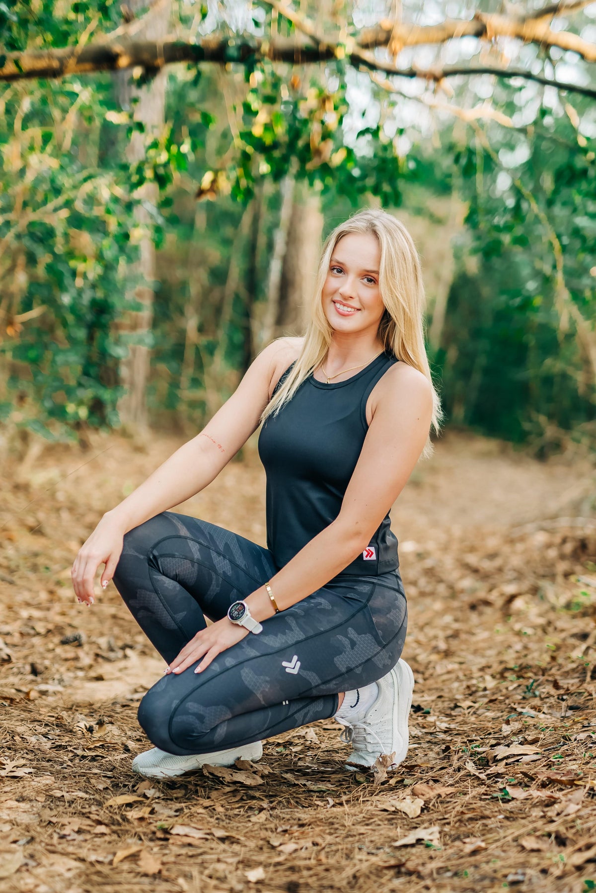 Woman wearing MOVE Sport Apparel women’s 25-Inch Running Tights in Black Camouflage during a woodland warm-up.
