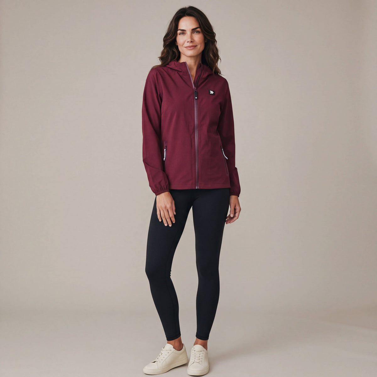 Full-body studio view of a woman wearing the Windsor Wine MOVE Sport Apparel women’s Soft Shell Jacket with black leggings and off-white trainers.