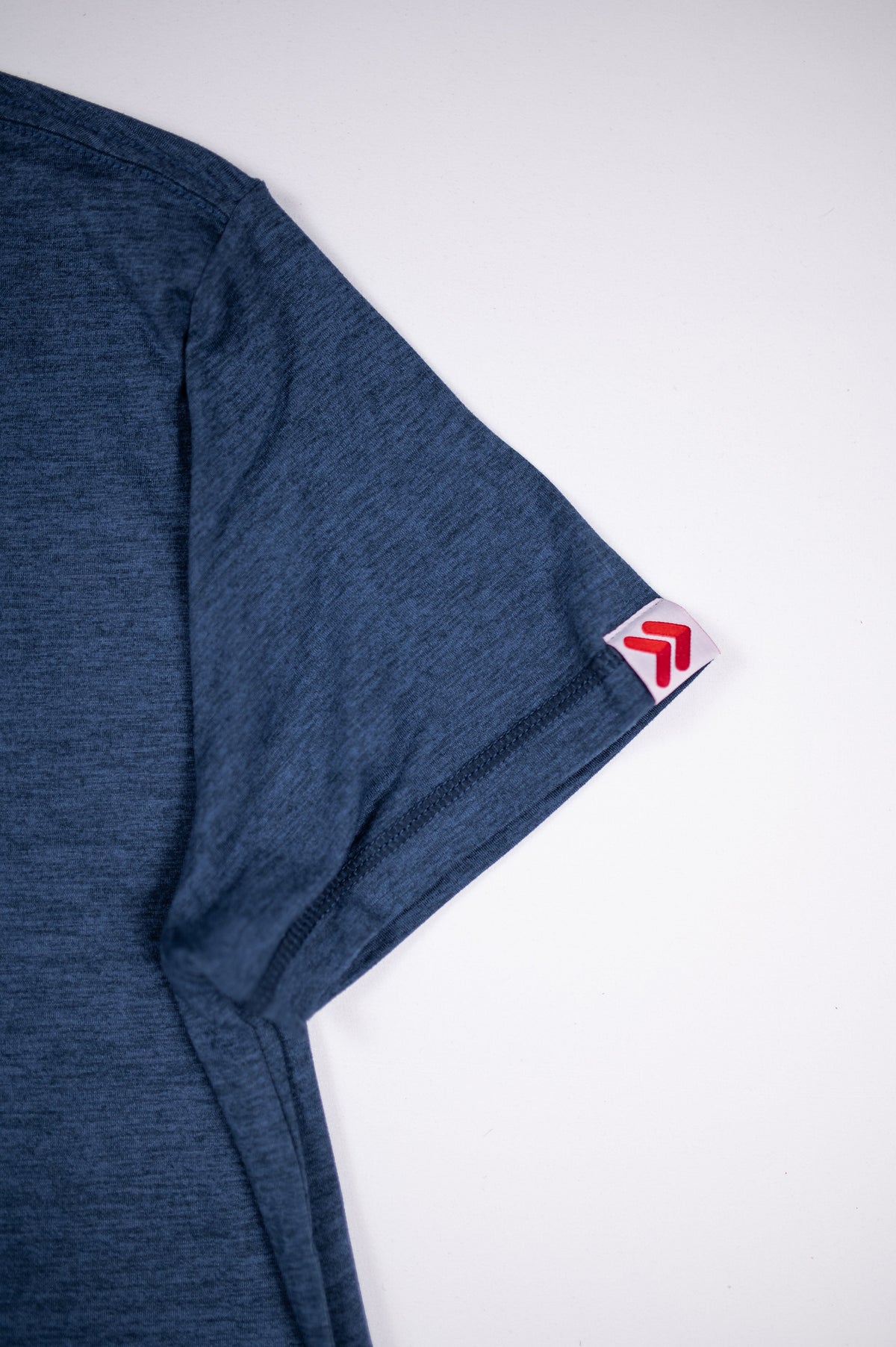 Close-up of the Pageant blue MOVE Sport Apparel women’s Essential Short Sleeve showing heathered fabric, sleeve stitching and red-and-white sleeve tag.