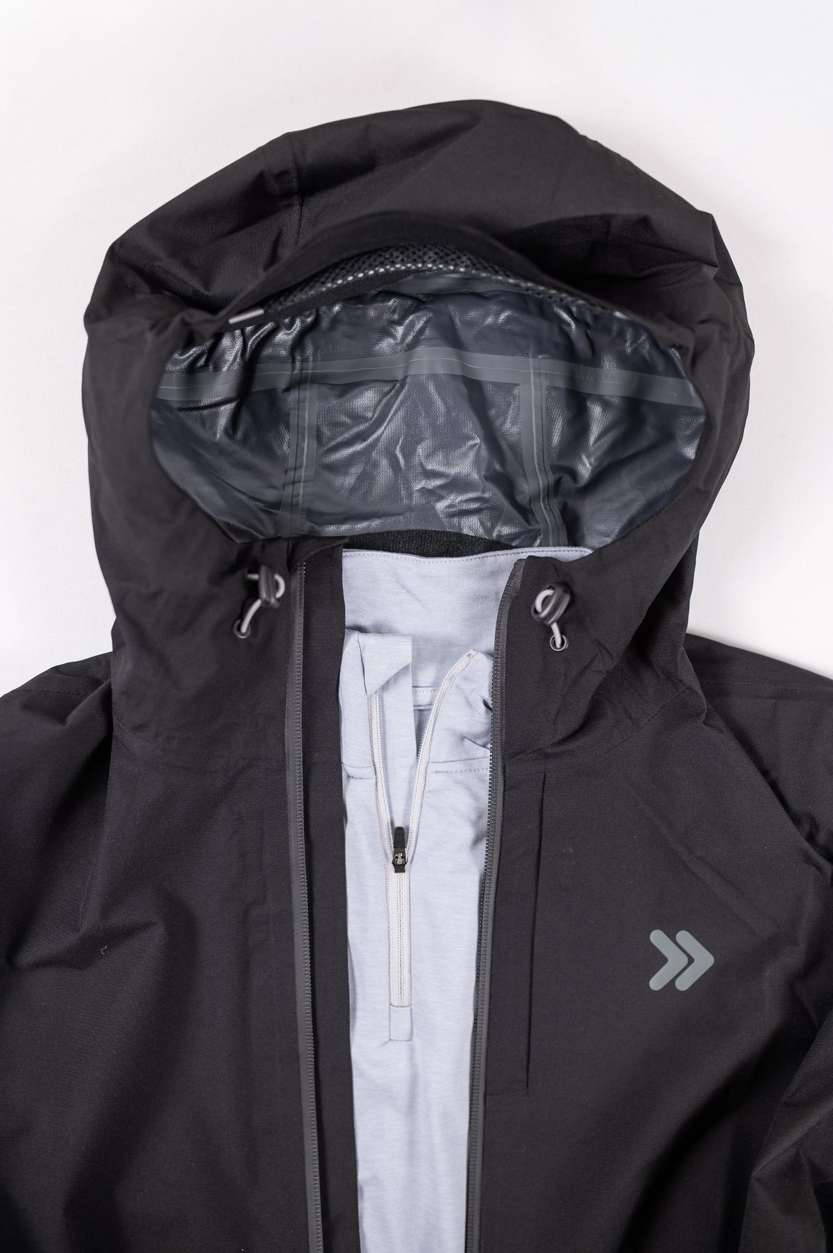 Close view of the black MOVE Sport Apparel women’s waterproof jacket hood, gray lining and chest embellishment.