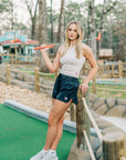 Woman wearing the MOVE Sport Apparel Women’s FlexRib Full Length Tank in Crystal Gray with dark running shorts at a mini-golf course.