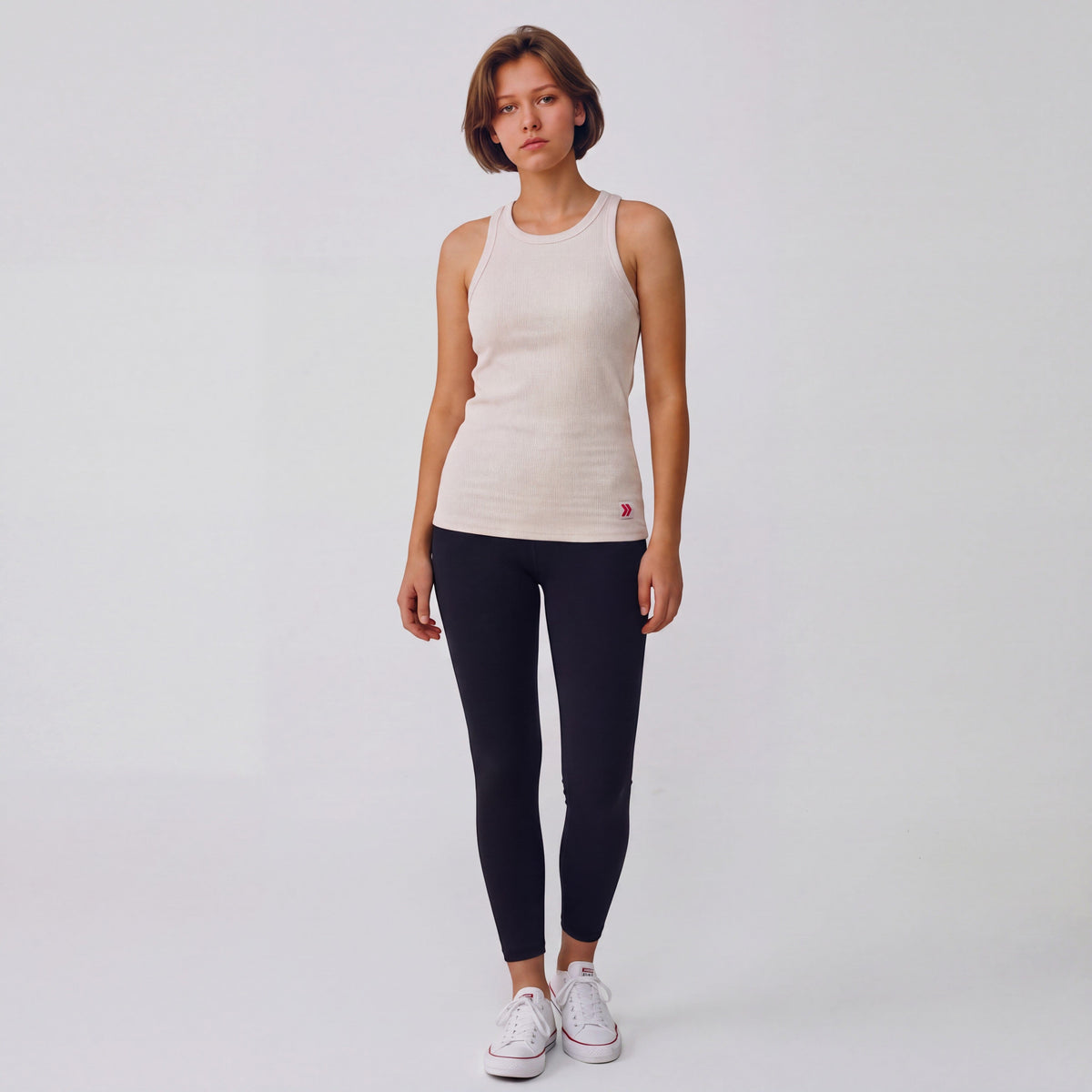 Full-body studio view of a woman wearing the MOVE Sport Apparel Women’s FlexRib Full Length Tank in Crystal Gray with black leggings and white trainers.