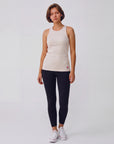Full-body studio view of a woman wearing the MOVE Sport Apparel Women’s FlexRib Full Length Tank in Crystal Gray with black leggings and white trainers.