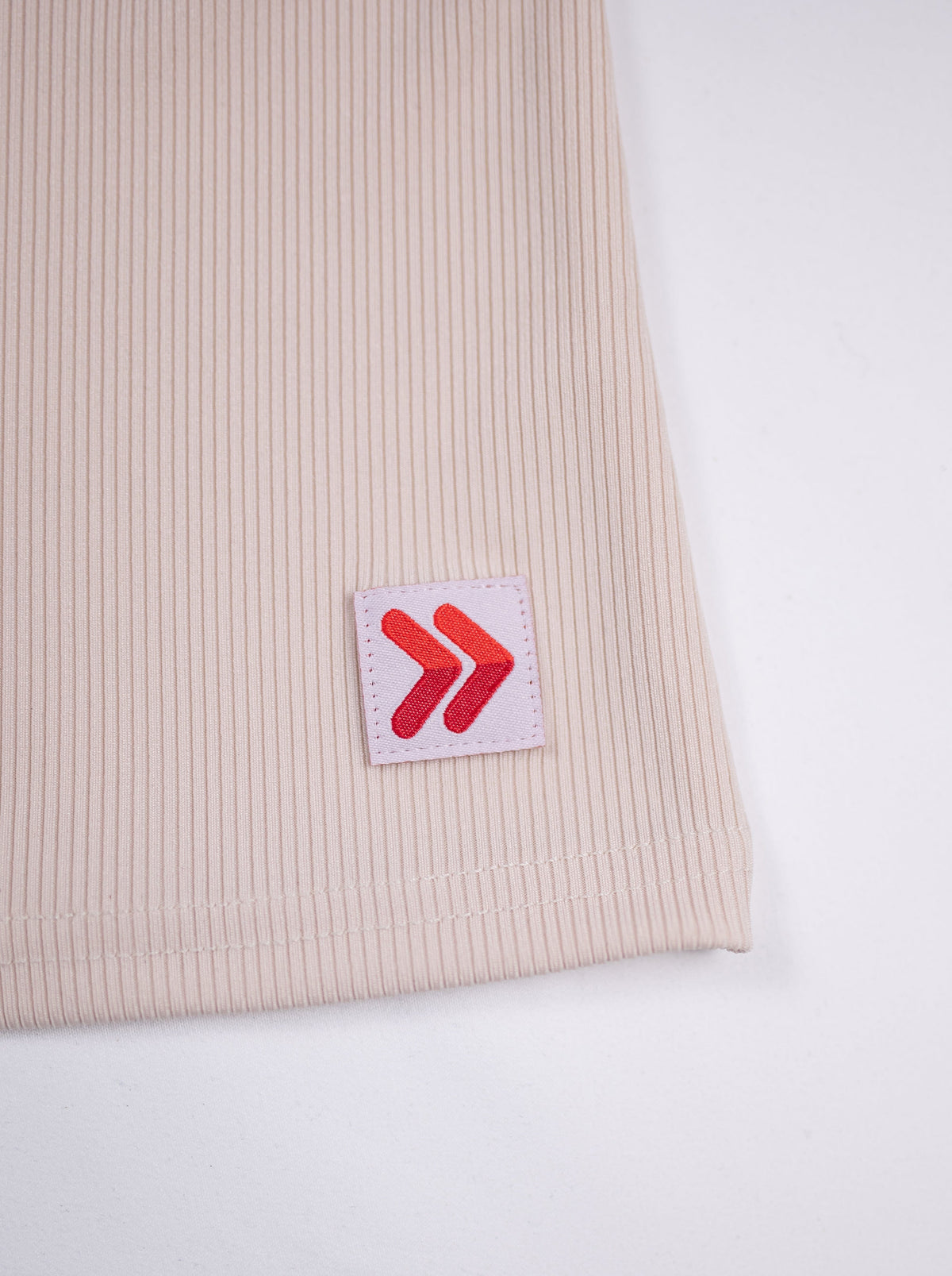Close view of ribbed fabric and the red-and-white hem tab on the Crystal Gray MOVE Sport Apparel Women’s FlexRib Full Length Tank.