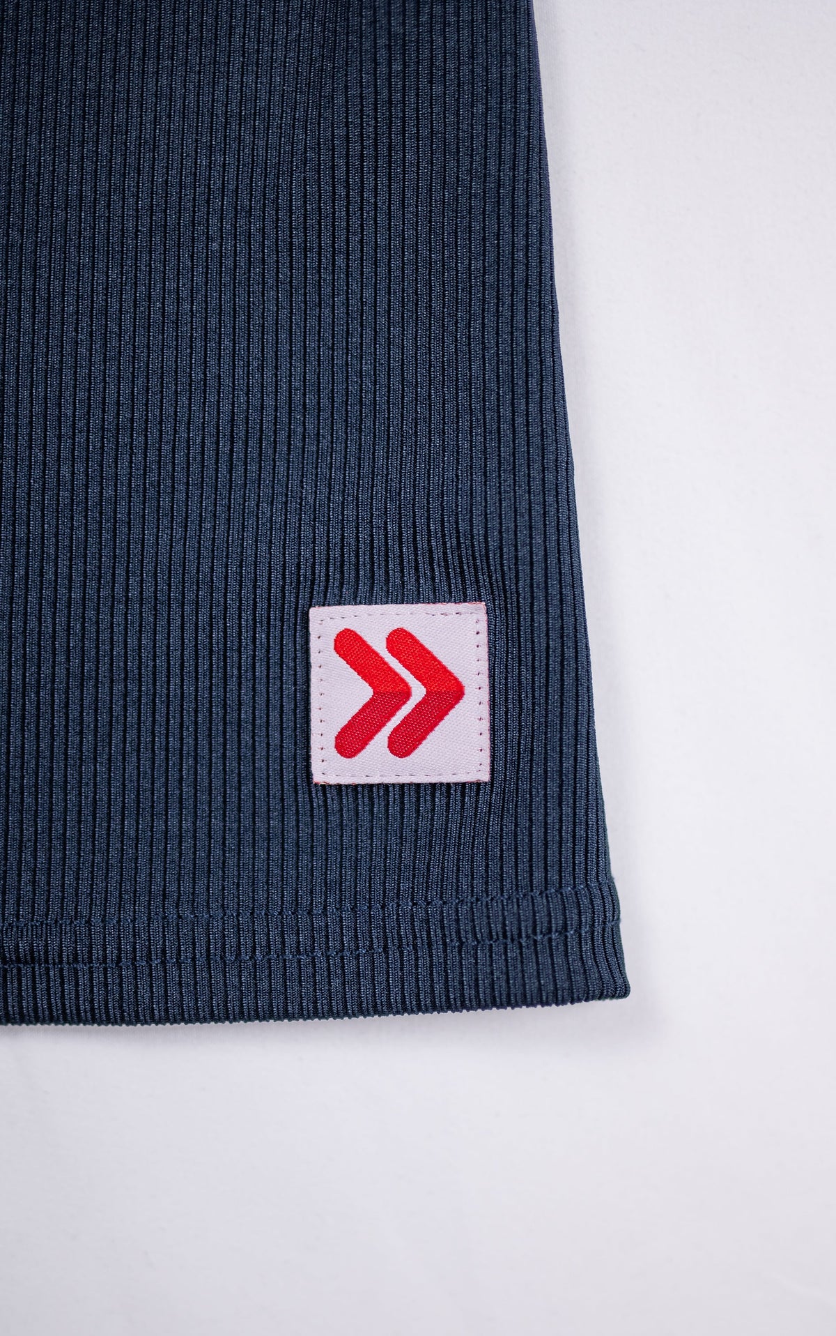 Close view of ribbing and the original red-and-white hem tab on the India Ink MOVE Sport Apparel Women’s FlexRib Full Length Tank.