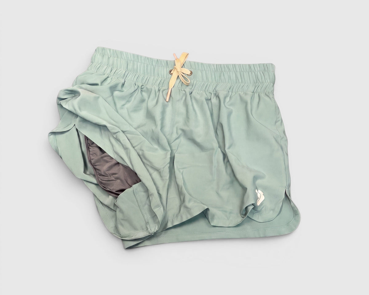 Pale green-blue running shorts lifted to show the inner lining and light drawstring.