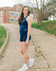 MOVE Sport Apparel women’s Biker Shorts: Woman wearing Maritime Blue biker shorts with a navy cropped tank beside a campus walkway.