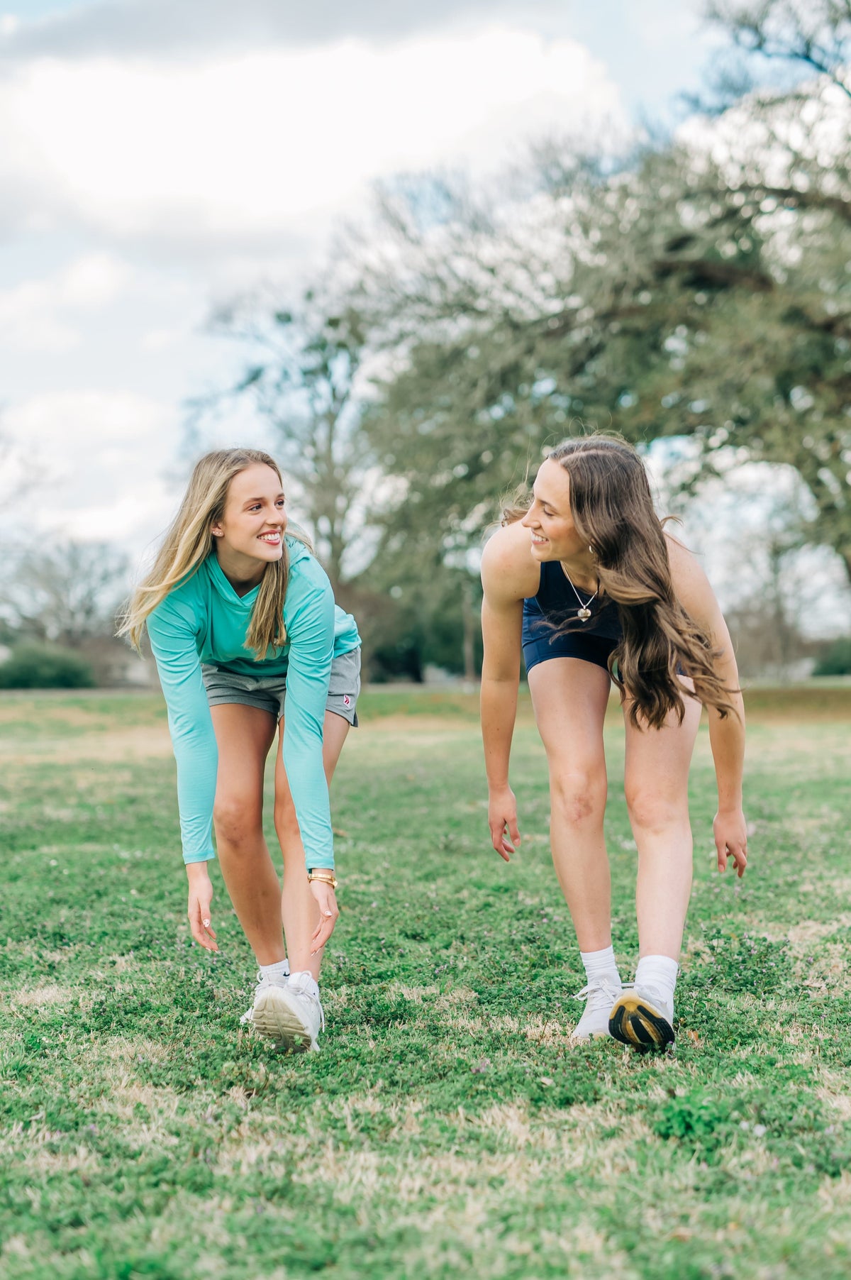 MOVE Sport Apparel women’s Biker Shorts: Woman wearing Maritime Blue biker shorts while stretching forward on a grass field.