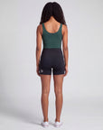 Rear studio view of a woman wearing black MOVE Sport Apparel Women’s Biker Shorts, showing the short inseam, rear waistband zipper and silver embellishment near the back hem.