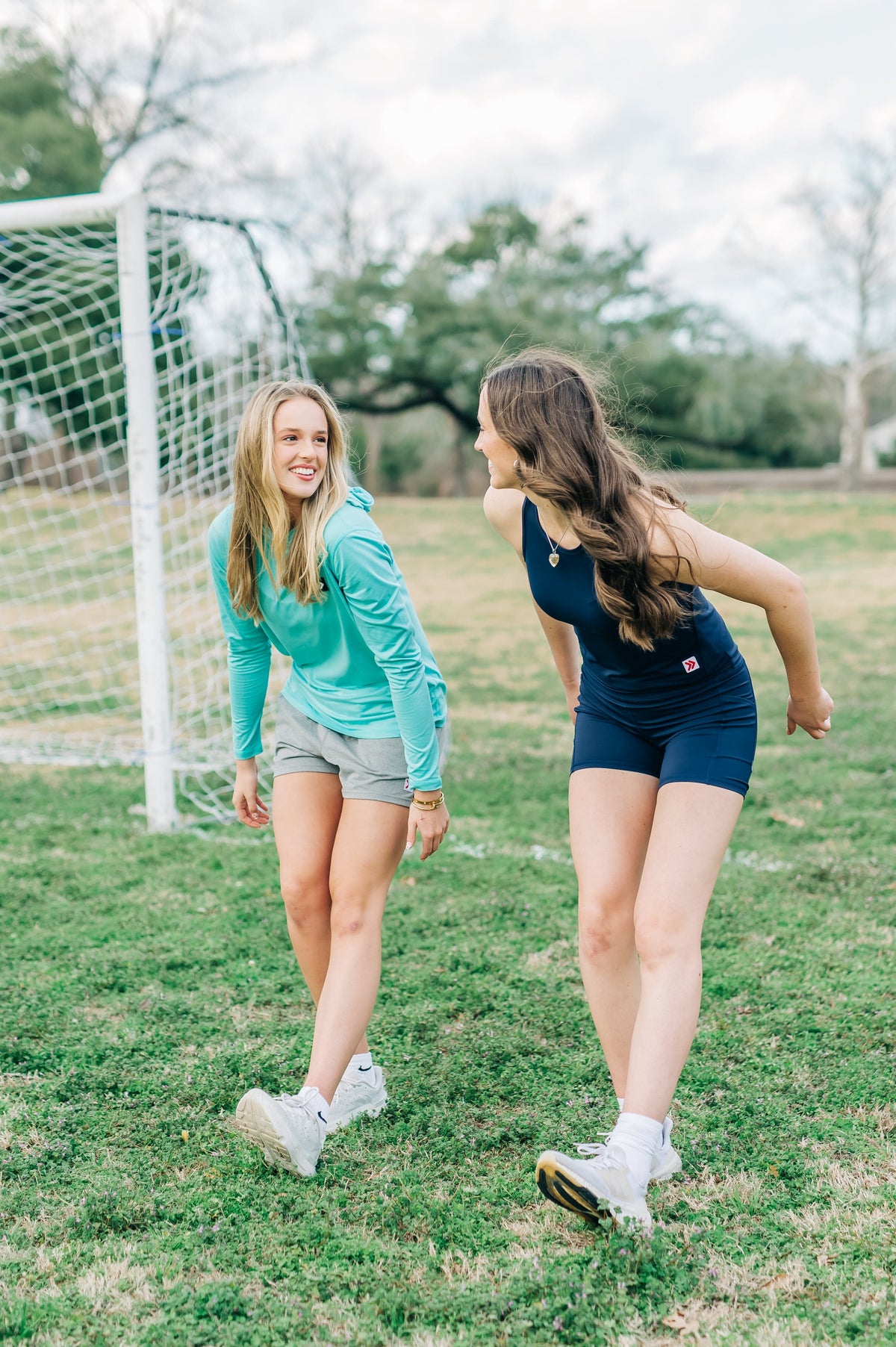 MOVE Sport Apparel women’s Black Label Lightweight Sun Hoodie: Woman wearing Aqua Splash sun hoodie stepping forward during a field warm-up.