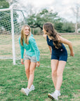 MOVE Sport Apparel women’s Black Label Lightweight Sun Hoodie: Woman wearing Aqua Splash sun hoodie stepping forward during a field warm-up.