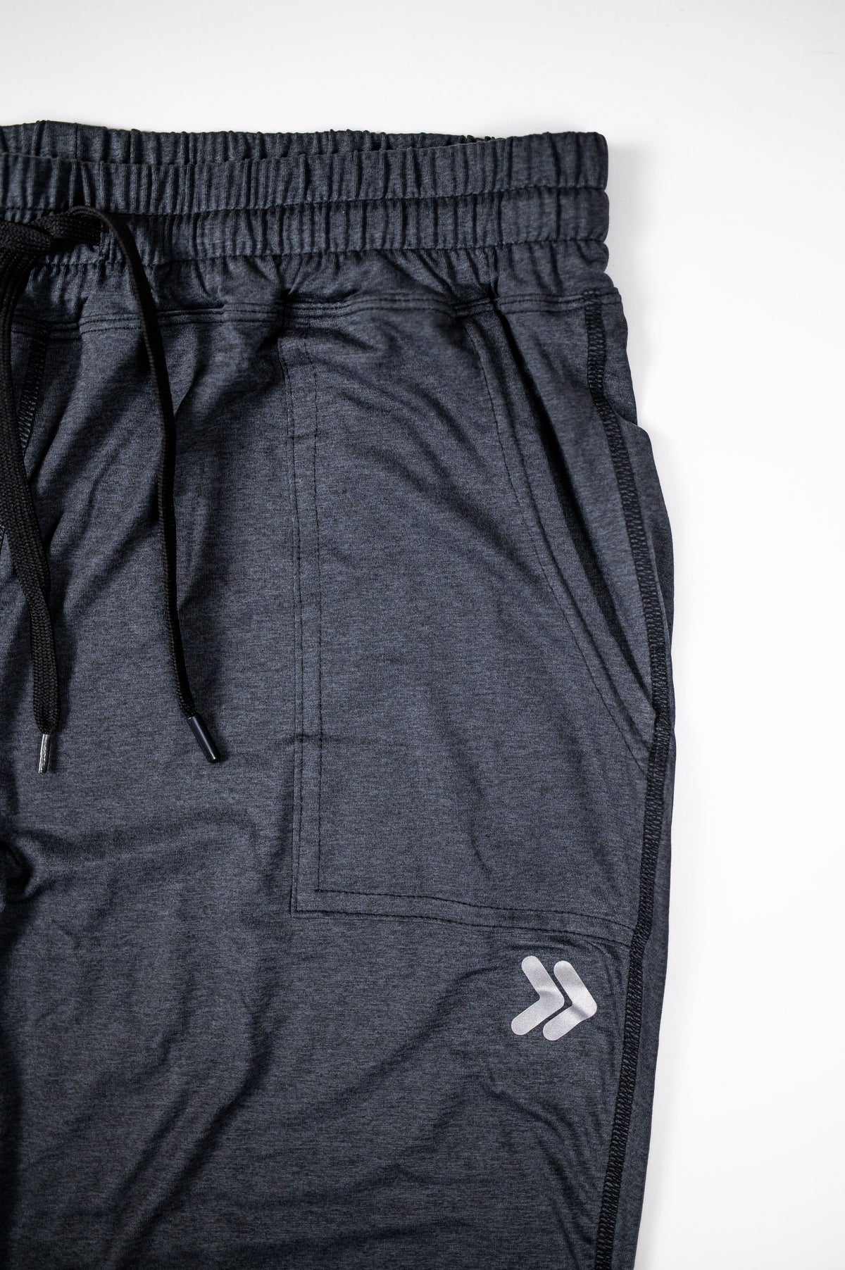 Black Essential Joggers showing elastic waistband, drawstring, pocket and original thigh embellishment.