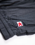 Close-up of fabric stitching and the original red double-chevron tab on black Essential Joggers.