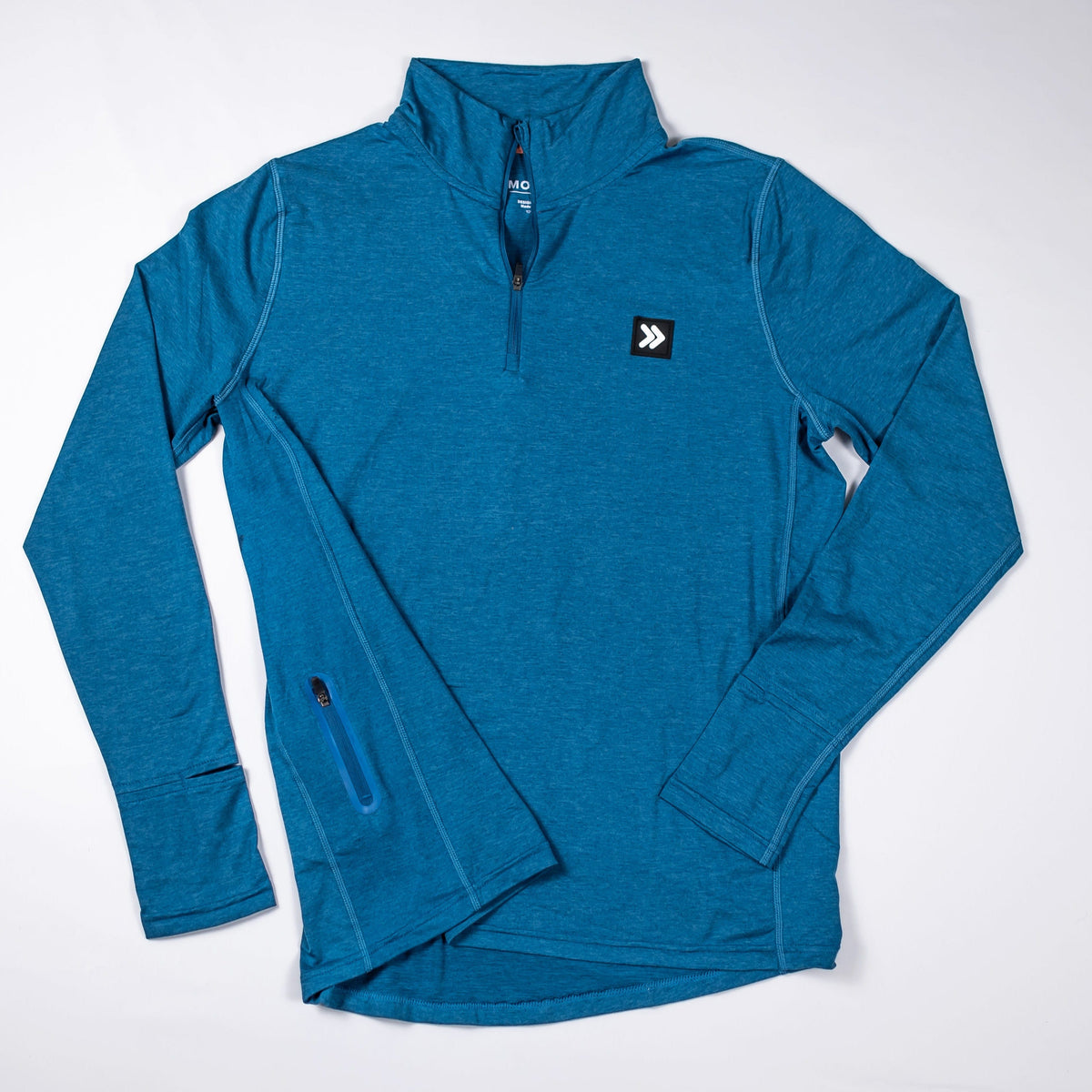 MOVE Sport Apparel Women’s Essential Quarter Zip Pro: Blue Heather Ashes laid flat from the front, showing the quarter zipper, chest patch and side pocket.