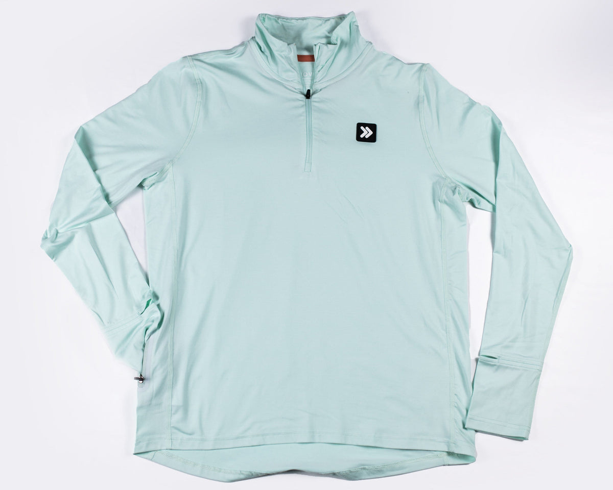 MOVE Sport Apparel Women’s Essential Quarter Zip Pro: Heather Skylight laid flat from the front, showing the quarter zipper and original black chest patch.