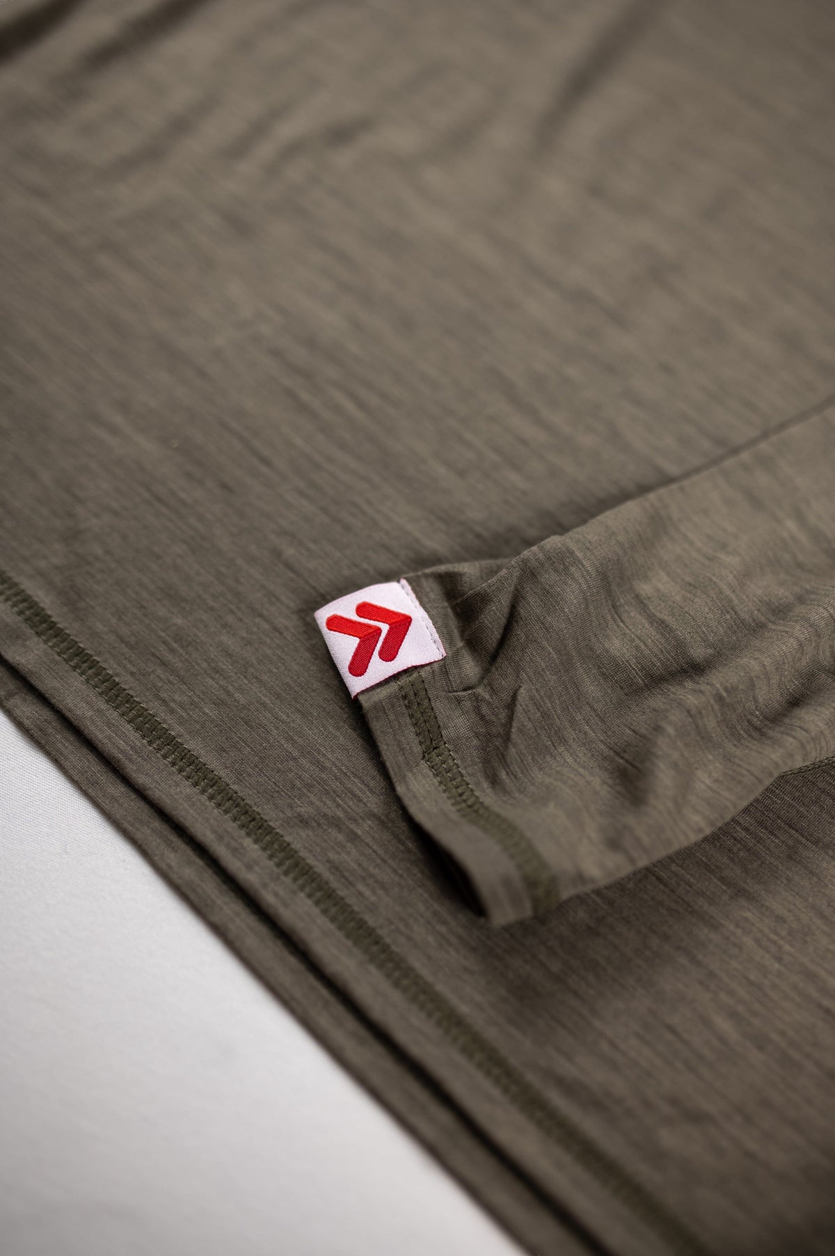 Close view of the original red-and-white cuff label on the MOVE Sport Apparel Women’s Long Sleeve Merino Base Layer Shirt in Smokey Olive.