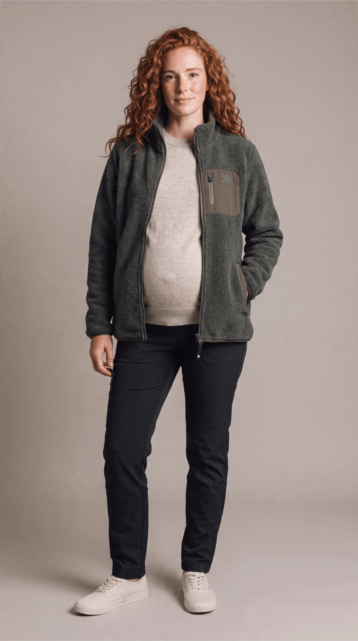 Full-length studio view of a woman wearing the Smokey Olive MOVE Sport Apparel Sherpa jacket over an oatmeal knit top.