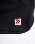 Close-up of the original white square with red double chevrons on the black skort hem.