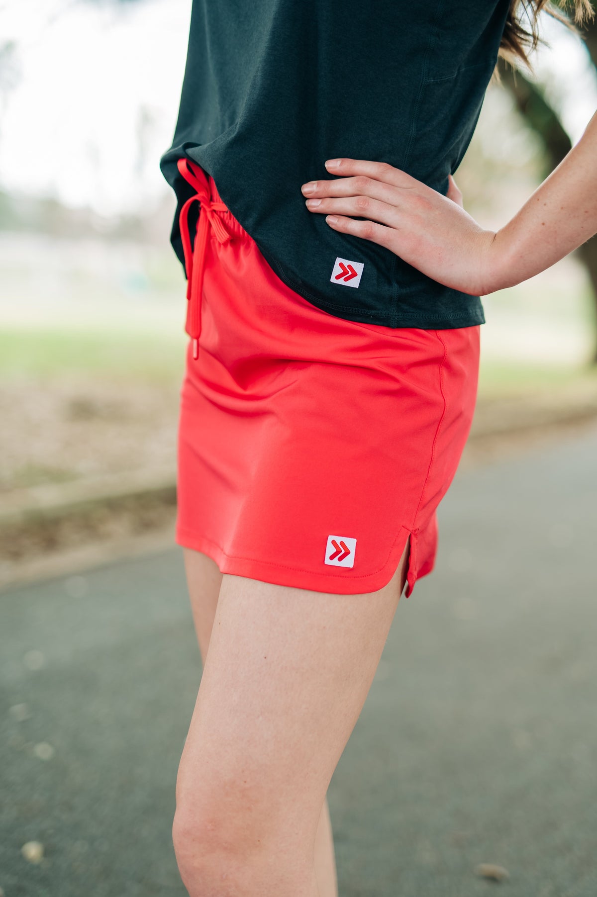 Coral-pink skort and black sleeveless top worn outdoors, showing original hem embellishments.