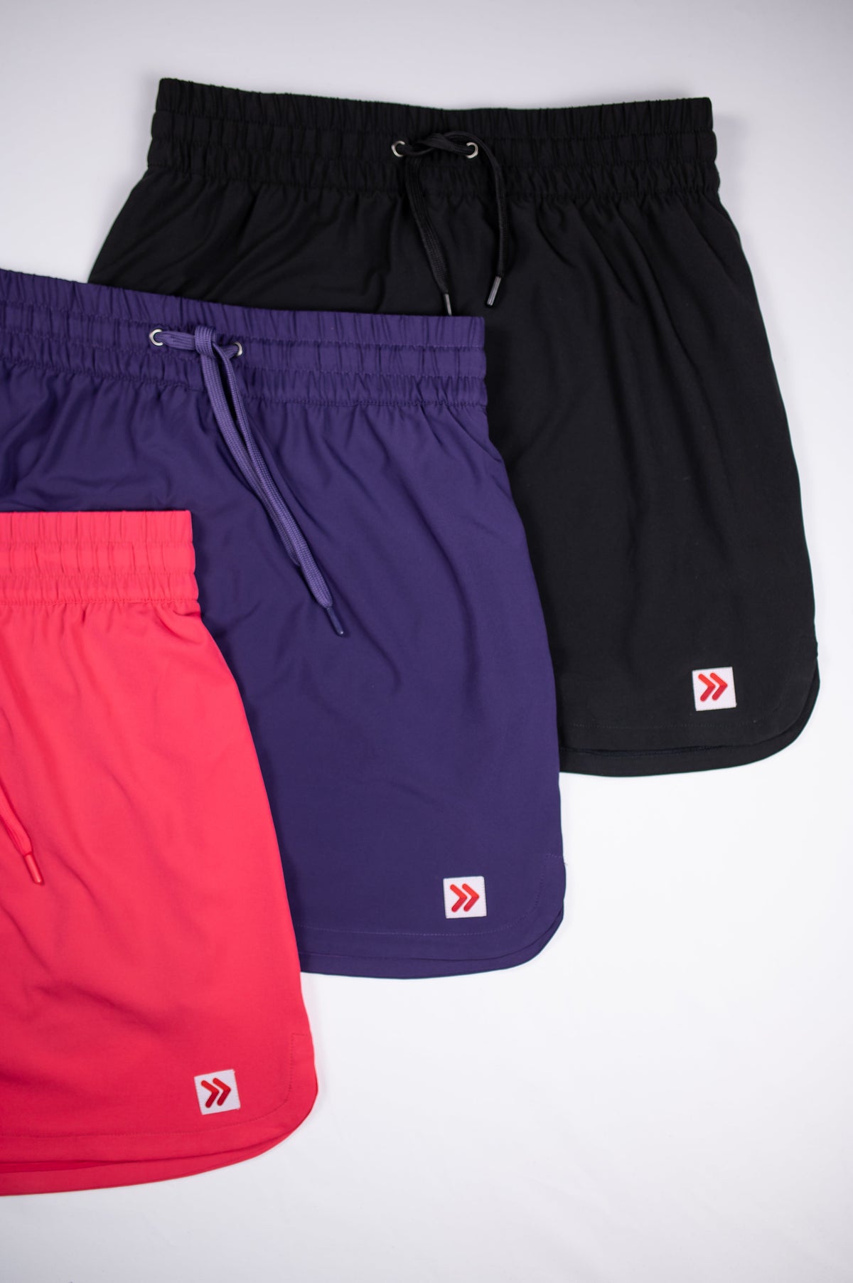 Hem and original double-chevron tab comparison across pink, purple and black skorts.